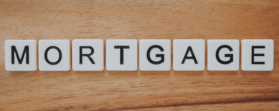 The word MORTGAGE written with scrabble like letters on a wooden surface